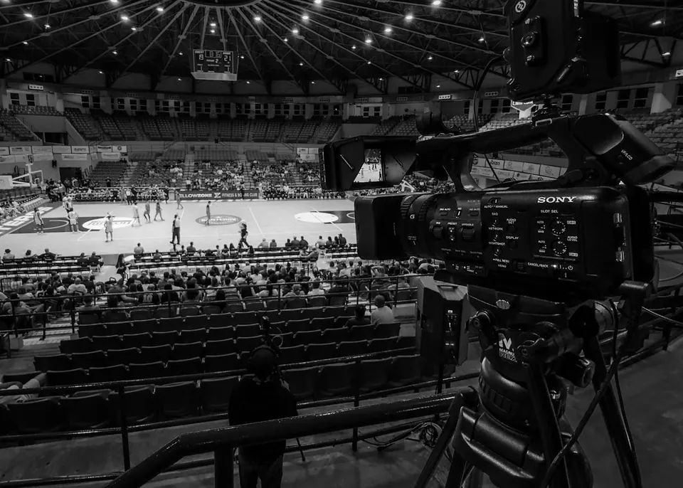 Cámara profesional en trípode con vista a una cancha de baloncesto
